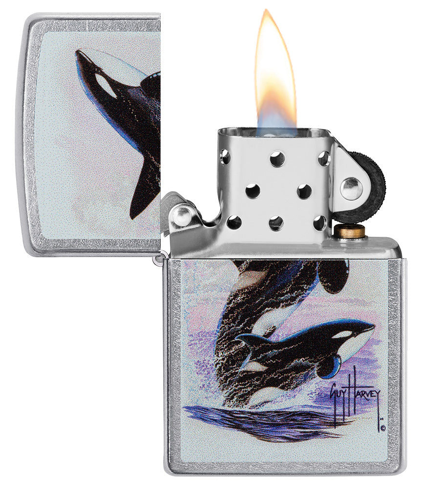 Zippo aansteker vooraanzicht chroom open en aangestoken met gekleurde illustratie van twee orka's getekend door Guy Harvey