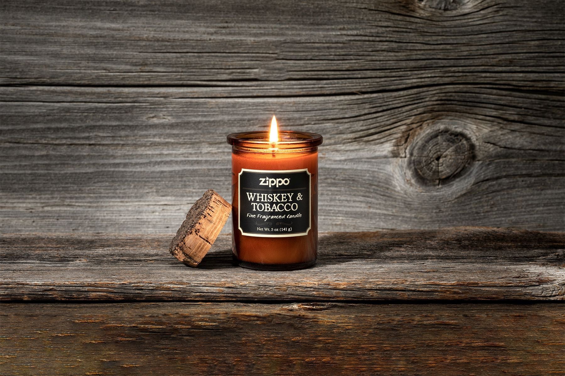 Zippo-kaars Whiskey & Tobacco bruin met kurken deksel met vlam tegen houten achtergrond