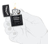 Vooraanzicht Zippo-aansteker zwart mat met Jack Daniel's-logo open met vlam in handpalm