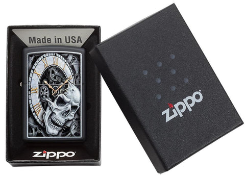 Zippo-aansteker zwarte klok waaruit een doodshoofd tevoorschijn komt met tandwielen op de achtergrond in open geschenkdoos