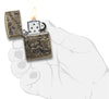 Zippo-aansteker antiek messing met diep gegraveerde doodshoofden open met vlam in handpalm